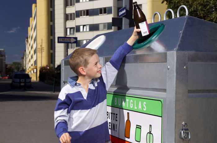 Kind schmeit Flasche in Container